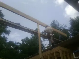 Carpenter setting a ridge beam over a new addition frame — Ice Dam Removal by Roofing Brothers in Sims