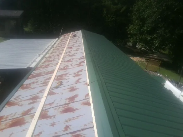 Old rusted panels beside newly installed green metal roofing — Wind Damage Roof Repair by Roofing Brothers in Sims