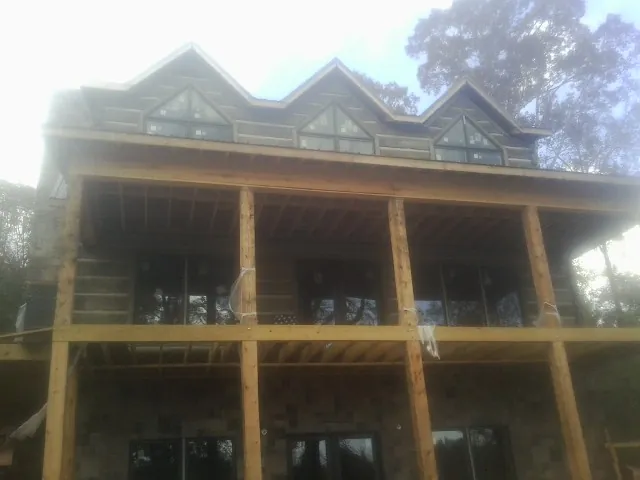Dormers and porch framing on a large log home under construction — Roof Coating work by our crew in Sims