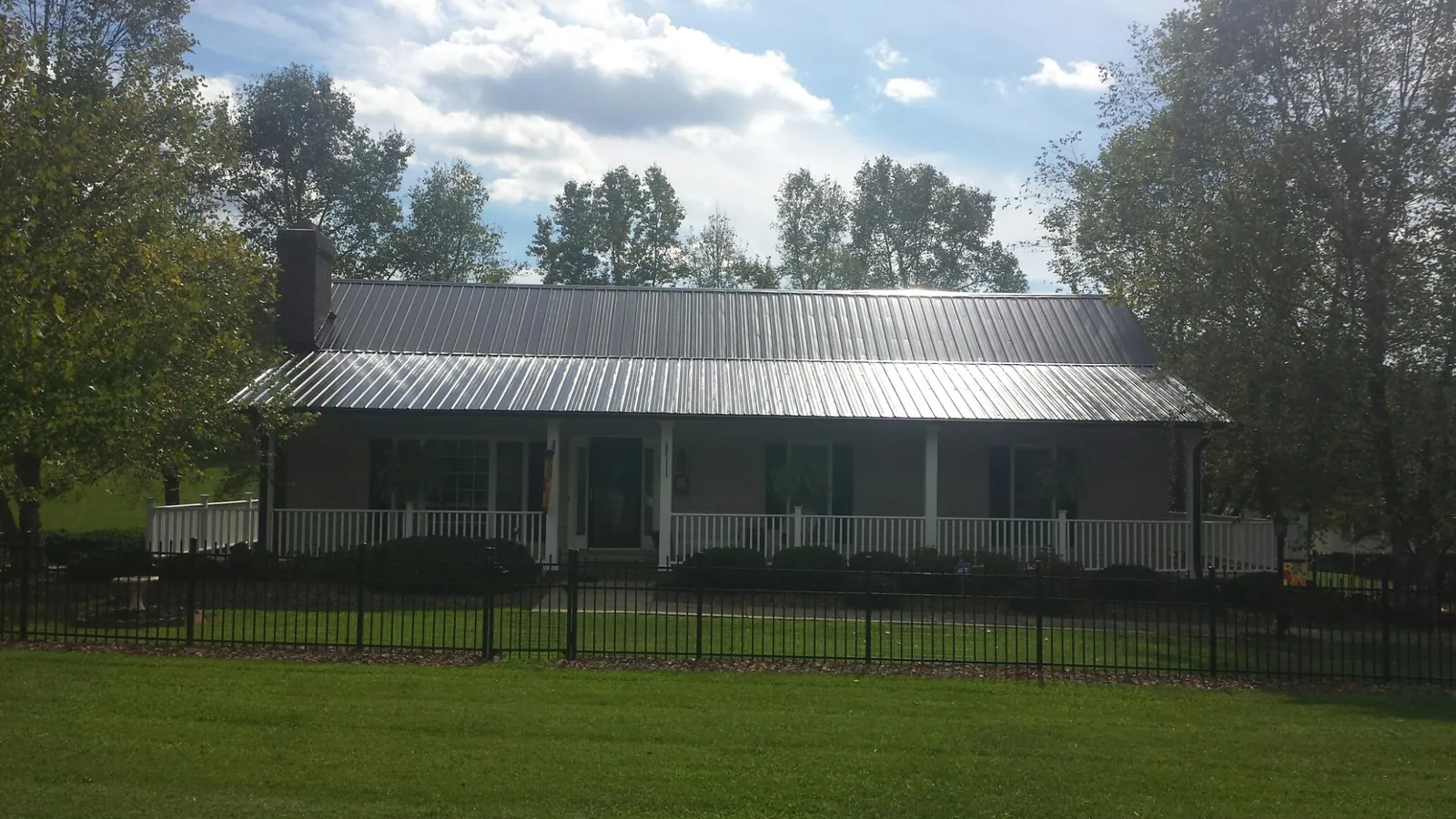 Gray metal roof on a brick ranch with a full width front porch — Gutter Guard Installation work by our crew in Sims